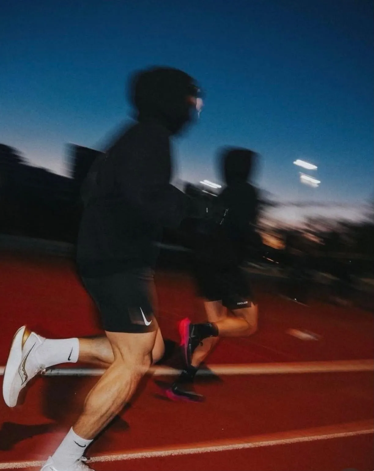 Corredores en una pista atlética al atardecer